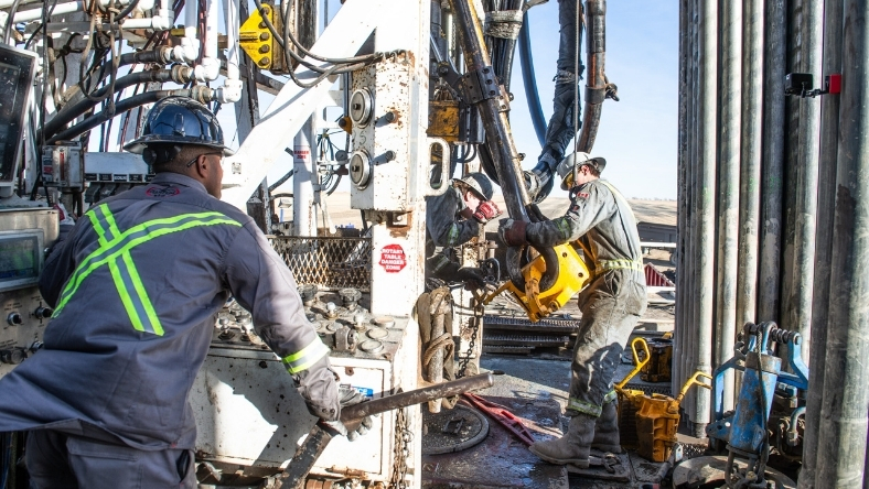 Workers operating drilling rig during natural hydrogen exploration