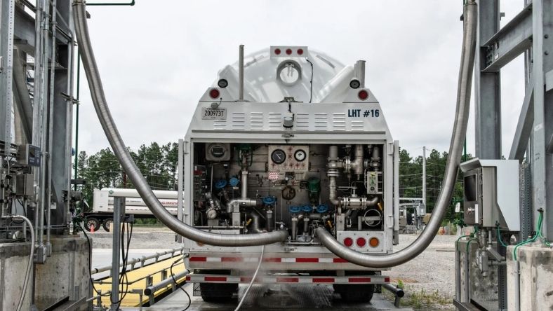 Industrial tanker truck connected to fuel transfer system with hoses and control valves