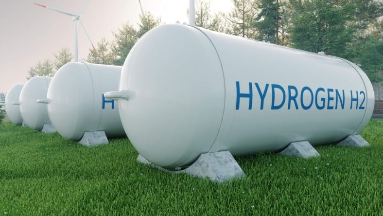 Hydrogen storage tanks labeled H2 with wind turbines in background