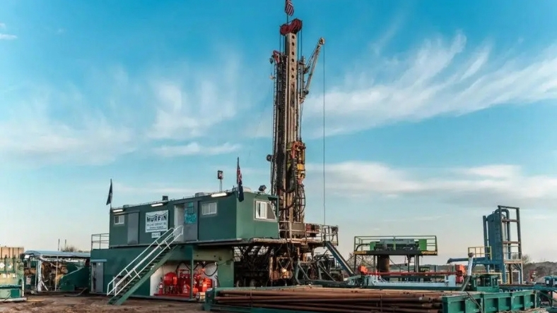 Land-based drilling rig on open plains under blue sky