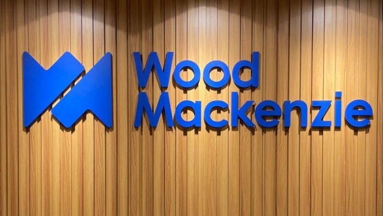 Wood Mackenzie blue raised logo on spotlight-lit wooden panel wall